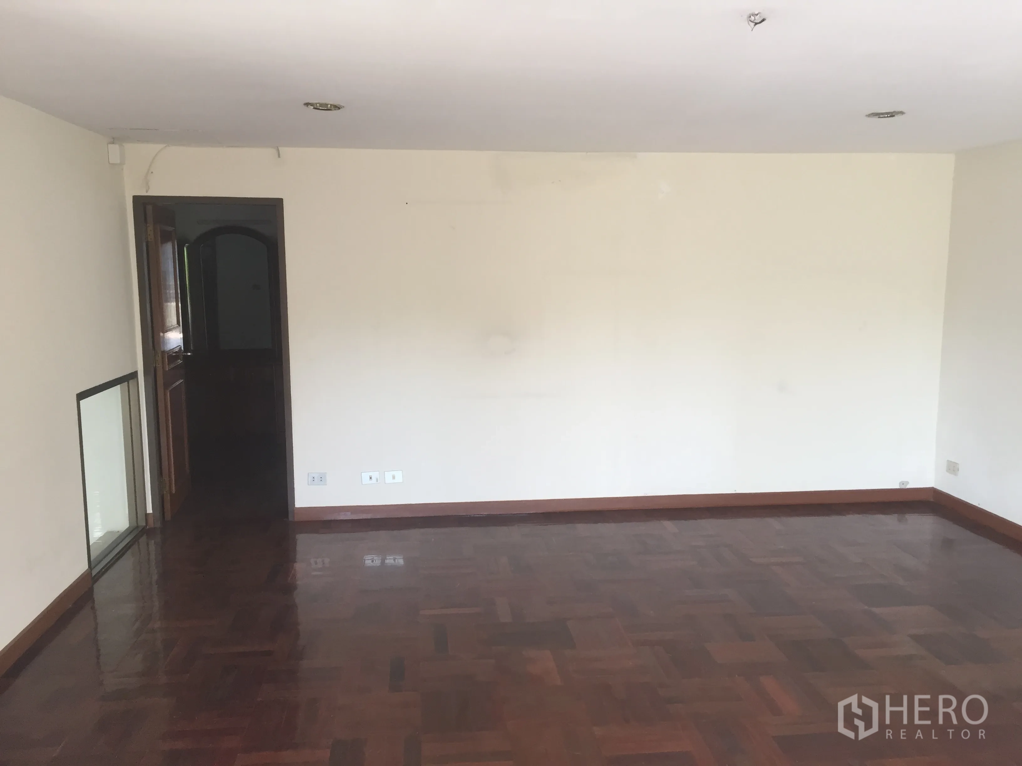 带办公室的家 出售在Watthana, Bangkok - 空房间，深色拼花木地板与白墙，木门入口。