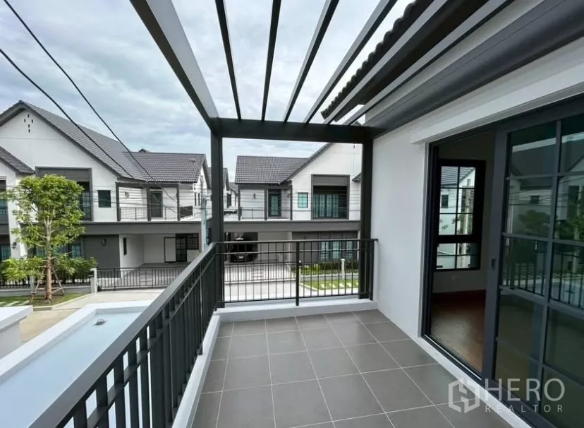 Detached House for rent in Bang Phli, Samut Prakan - Covered upper balcony with pergola roof and metal railing overlooking the neighborhood.