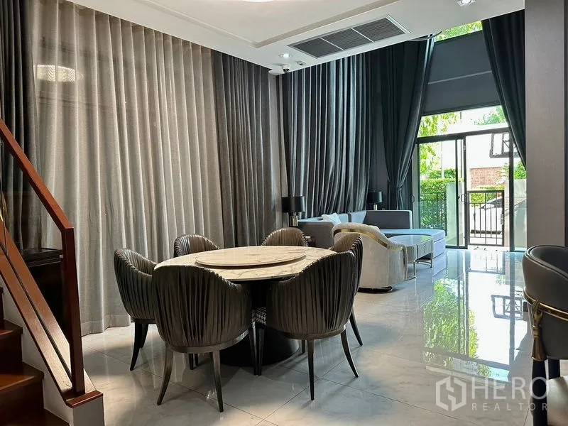 Detached House for rent in Phra Khanong, Bangkok - Dining zone with round marble table, velvet chairs, and tall curtains.