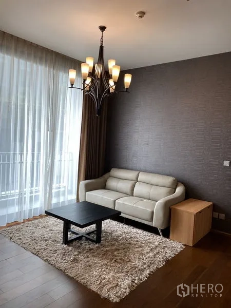 Condominium for rent in Watthana, Bangkok - Cozy living corner with cream sofa, shag rug, chandelier and sliding door to the balcony.