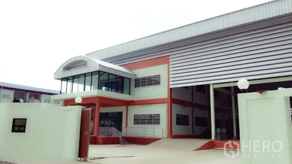 Factory for sale in Pathum Thani - Modern factory exterior with corner glass office, large roller shutter and ramp in Khlong Luang.