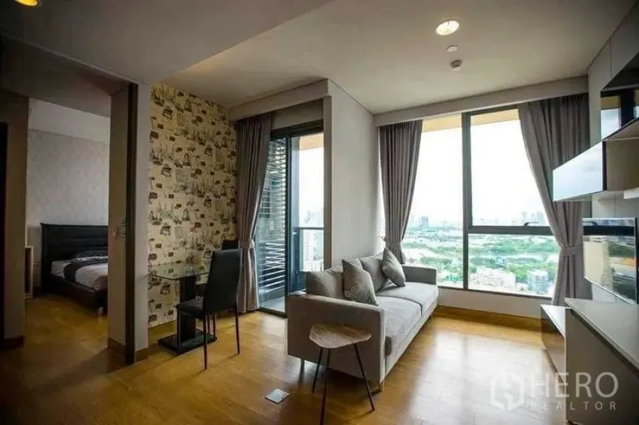 Condominium for rent in Khlong Toei, Bangkok - Open-plan living room connecting to the bedroom, with balcony and floor-to-ceiling windows.
