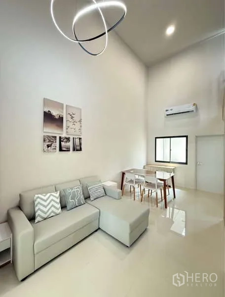 Townhouse for rent in Bang Phli, Samut Prakan - Living room with sectional sofa, modern pendant light and dining set.