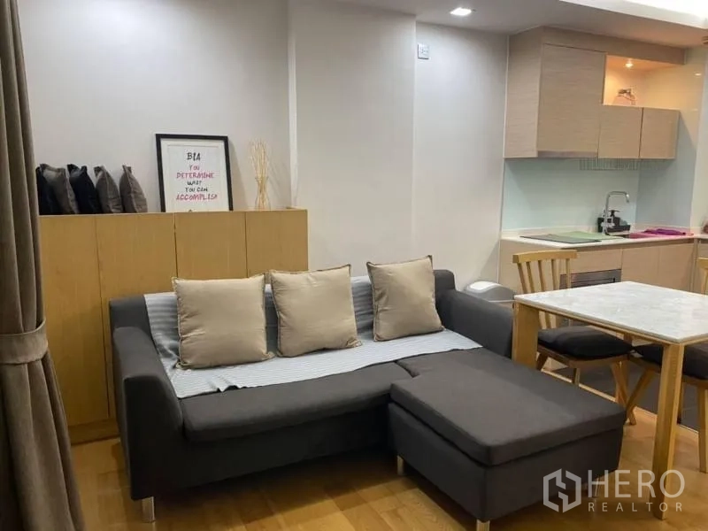 公寓 出租在Watthana, Bangkok - 开放式客厅，转角沙发、餐桌与小厨房