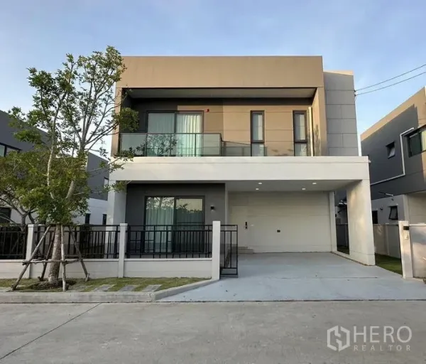 Detached House for rent in Bang Phli, Samut Prakan - Modern two-storey detached house facade with balcony, fenced yard and covered parking.