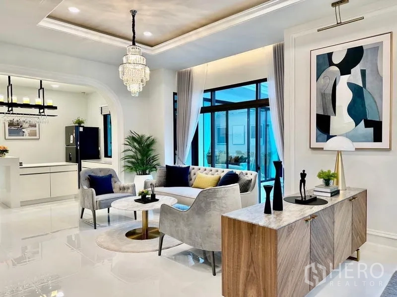 独立式住宅 出租在Lat Krabang, Bangkok - 起居室连拱门通向简约厨房，边柜与艺术画