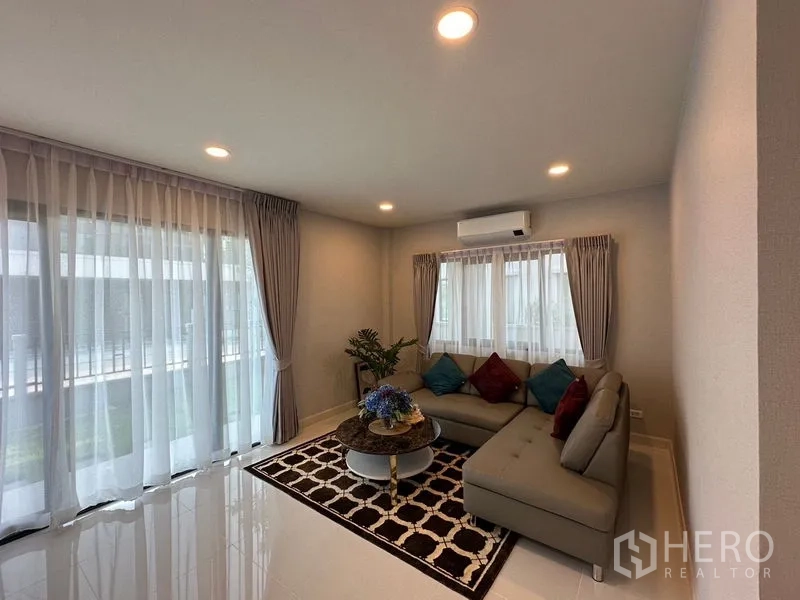 Detached House for rent in Bang Phli, Samut Prakan - Living area with floor-to-ceiling sheer curtains, recessed lighting and bright tiled floors.