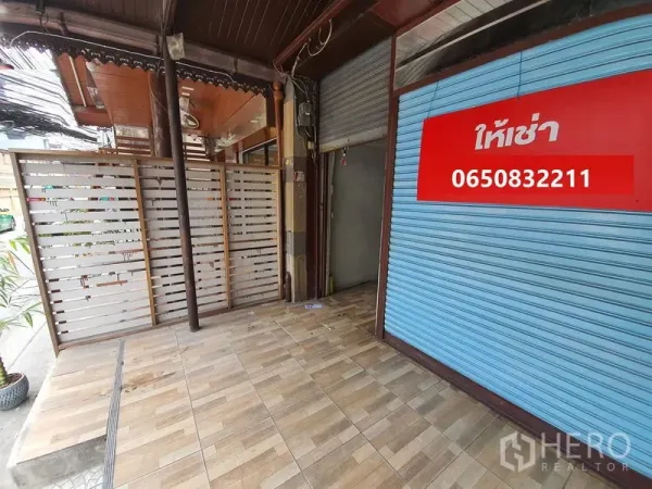 店屋 出租在Bang Rak, Bangkok - 临街店面门廊，木纹地砖与蓝色卷帘门，挂有出租标识。