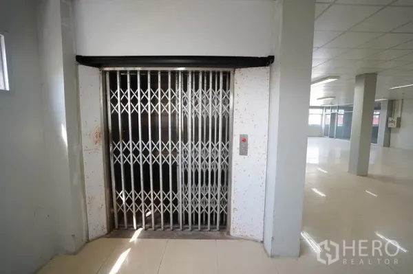 Factory for sale in Khlong Luang, Pathum Thani - 1.5-ton freight elevator with accordion gate on the production floor.