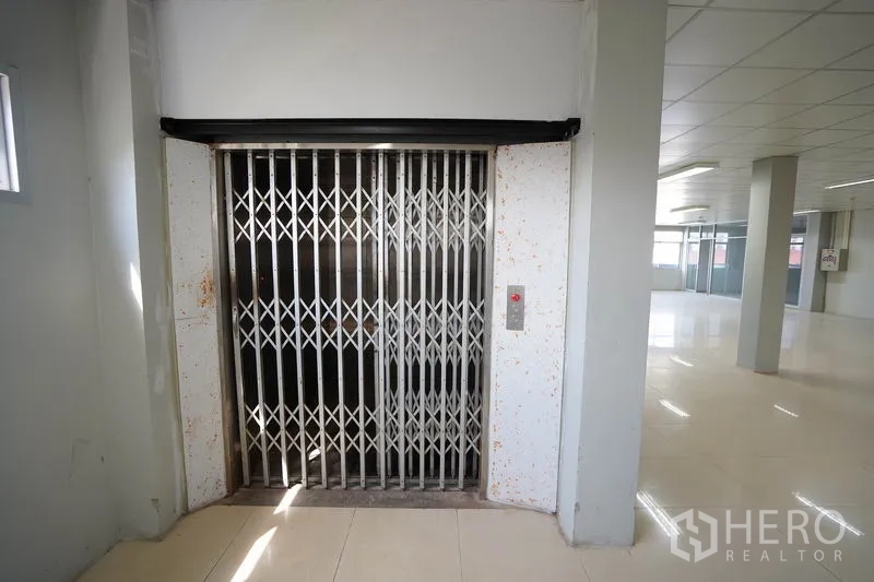 Factory for sale in Khlong Luang, Pathum Thani - 1.5-ton freight elevator with accordion gate on the production floor.