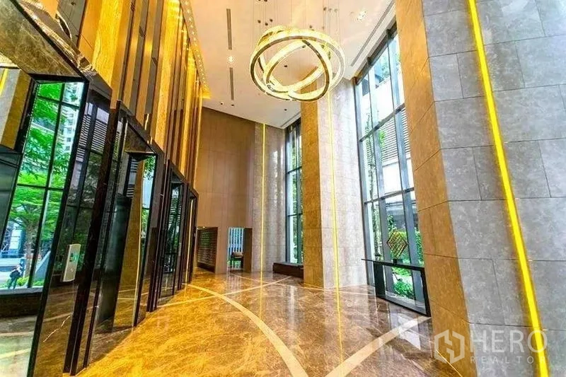 Condominium for rent in Khlong Toei, Bangkok - Grand condominium lobby with marble floors, tall windows and modern ring chandelier.