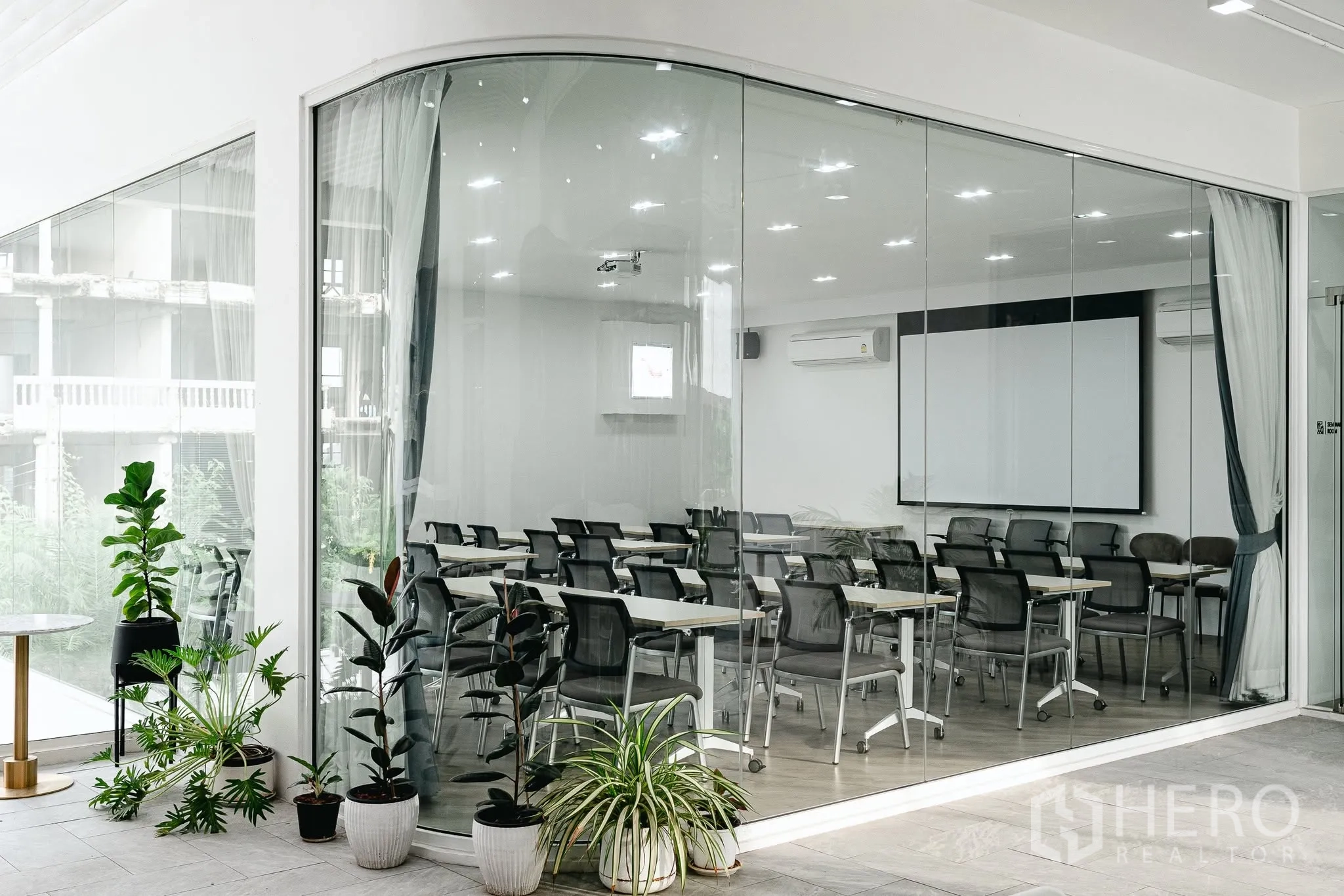 Office Space for rent in Bang Kapi, Bangkok - Glass-walled training room with rows of chairs, tables, projector screen, and air-conditioning.