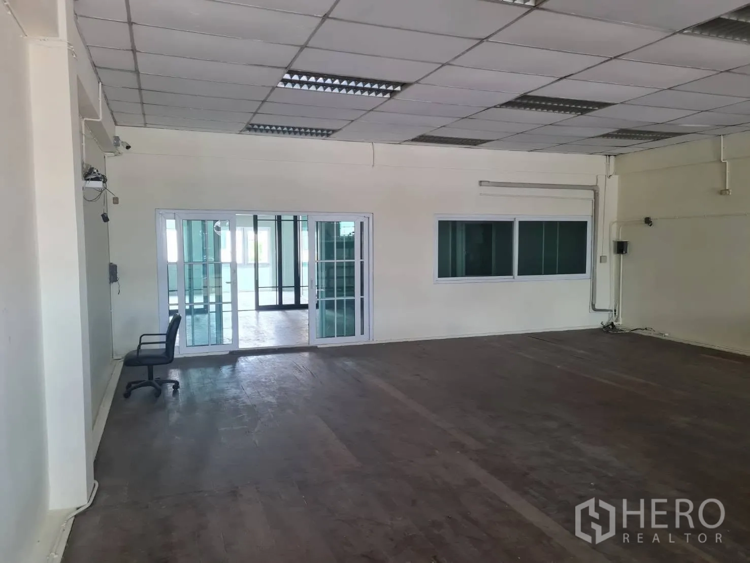 Warehouse for rent in Phra Pradaeng, Samut Prakan - Open interior workspace with drop ceiling, lighting, and glass doors to office.