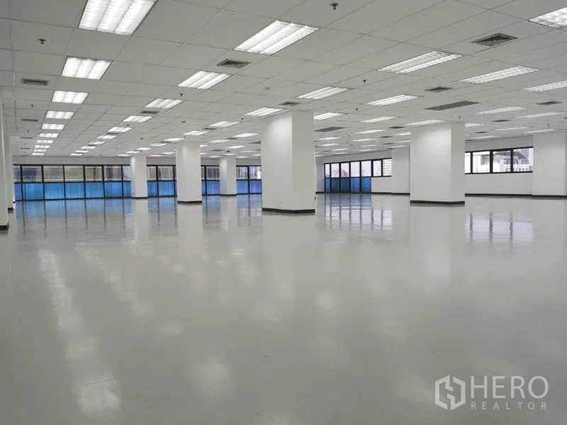 Office Space for rent in Phaya Thai, Bangkok - Spacious column‑grid office interior with blue‑tinted windows, fluorescent lighting and central air vents.