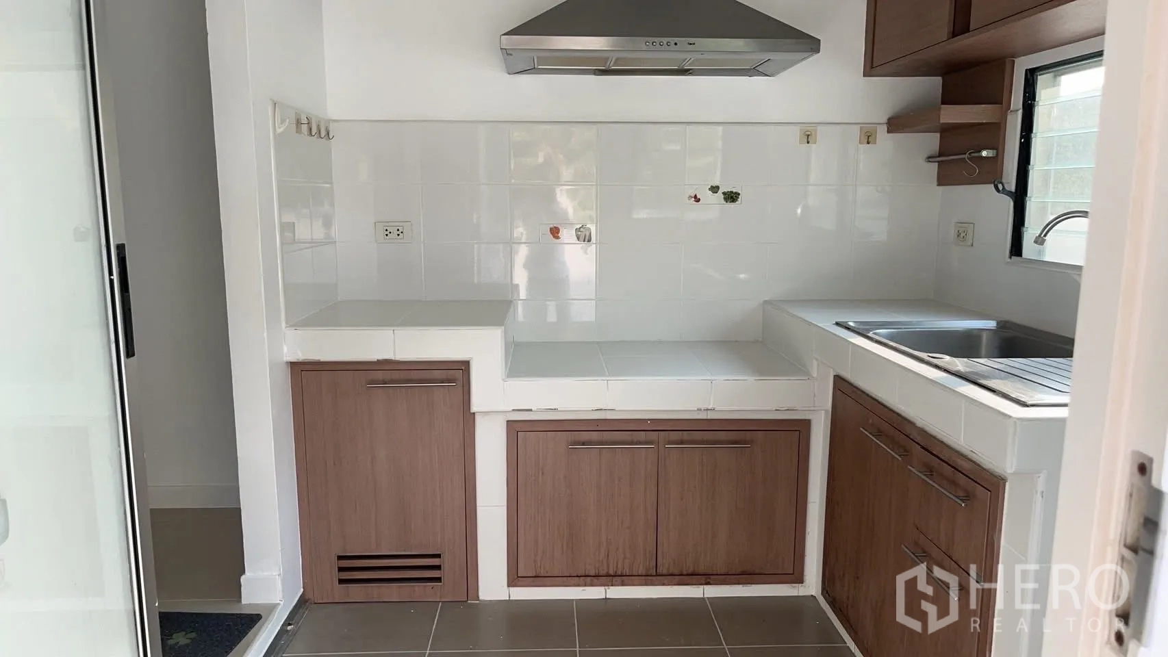 Detached House for rent in Bang Na, Bangkok - Fitted kitchen with range hood, tiled counters, sink, and wood cabinets.