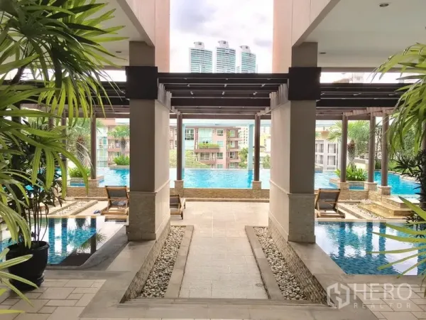 Condominium for rent in Khlong Toei, Bangkok - Resort-style condominium swimming pool with pergola, sun loungers and city views.