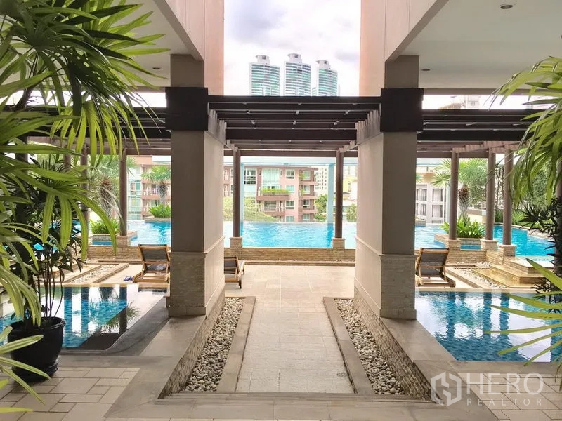 Condominium for rent in Khlong Toei, Bangkok - Resort-style condominium swimming pool with pergola, sun loungers and city views.