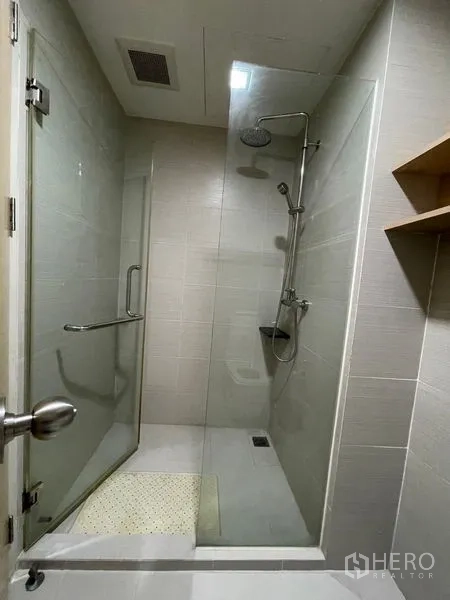 Condominium for sale in Khlong Toei, Bangkok - Modern bathroom featuring a glass-enclosed rain shower and light tiled walls.