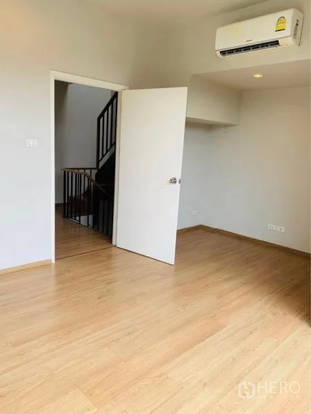 Home Office for rent - Air-conditioned bedroom with wood floor and white door leading to stair landing.
