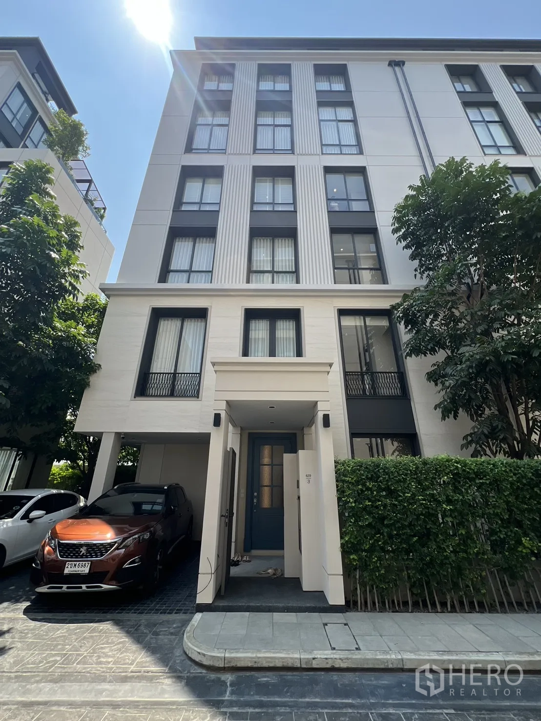 Semi-detached House for sale in Yan Nawa, Bangkok - Modern semi-detached house exterior with covered carport, hedges, and large windows.