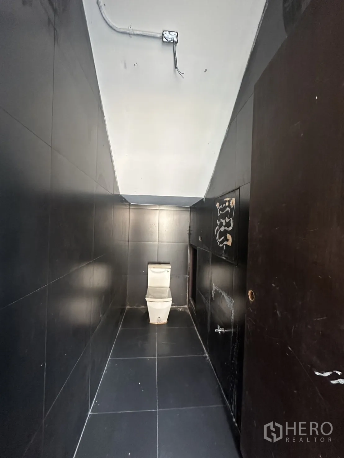 带办公室的家 出租在Pathum Wan, Bangkok - 狭长的黑色瓷砖卫生间，坐便器与外露管线。