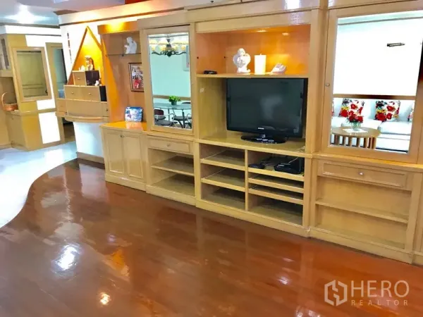 公寓 出租在Watthana, Bangkok - 客厅内定制木质电视墙与多层置物架，亮面木地板。