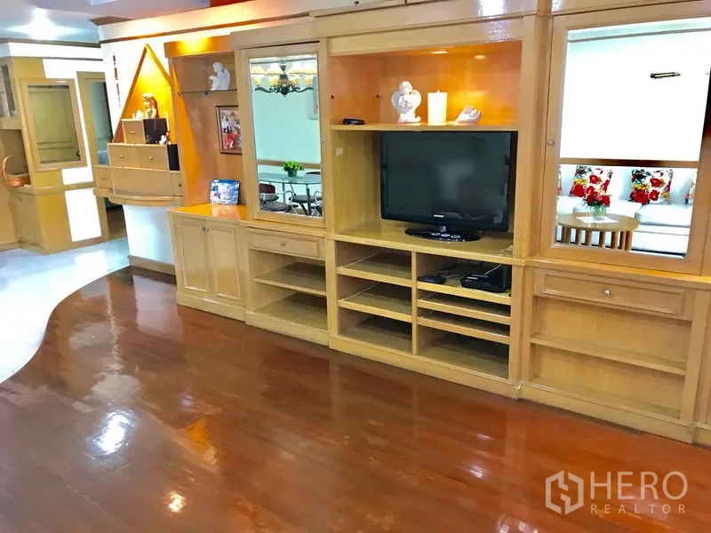 公寓 出租在Watthana, Bangkok - 客厅内定制木质电视墙与多层置物架，亮面木地板。