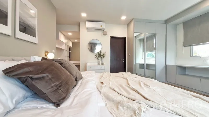 Condominium for rent in Khlong Toei, Bangkok - Master bedroom angle showing built-in wardrobes, dressing console, air conditioner and shelving.