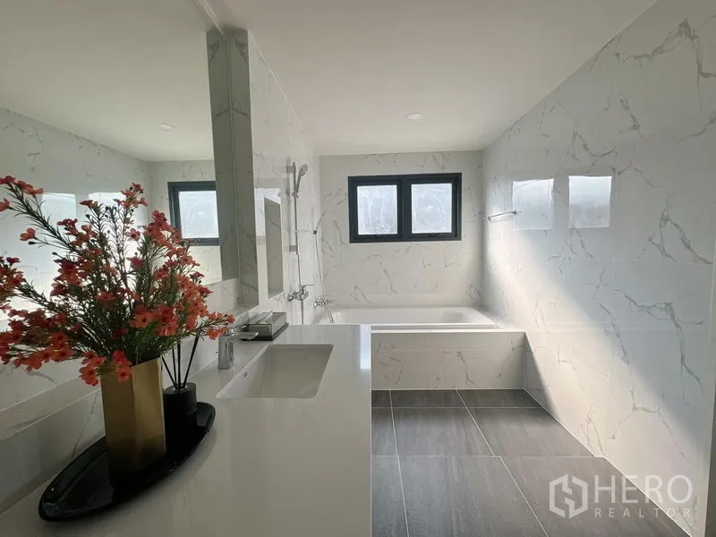 Detached House for rent or sale in Bang Phli, Samut Prakan - Modern bathroom with bathtub, marble-look walls, vanity and black-framed windows.