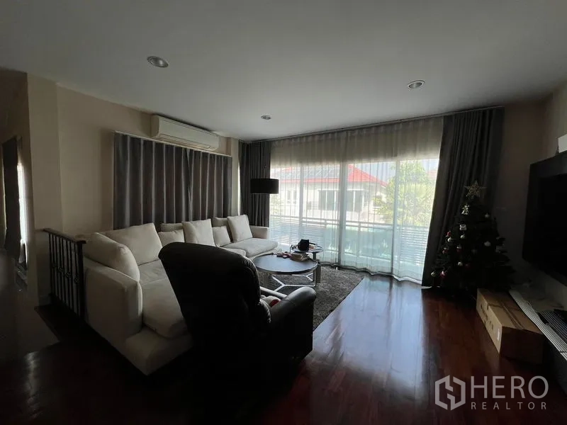 Detached House for rent or sale in Saphan Sung, Bangkok - Upstairs family lounge opening to balcony with full-height curtains and TV.
