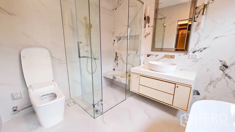 บ้าน ให้เช่าหรือขายในSaphan Sung, Bangkok - ห้องน้ำพร้อมตู้กระจกกั้นอาบน้ำ เคาน์เตอร์ซิงก์สีขาว และกระเบื้องลายหินอ่อน