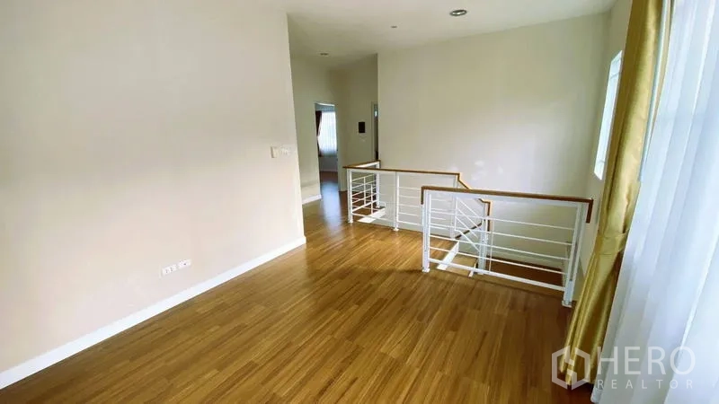 Detached House for rent in Bang Kapi, Bangkok - Bright upstairs landing with wooden flooring and white metal stair railing.