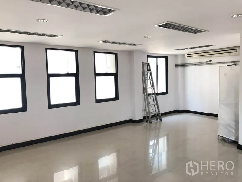 带办公室的家 出租在Wang Thonglang, Bangkok - 开放工作间，多扇黑框窗、亮面地砖与吊顶照明。