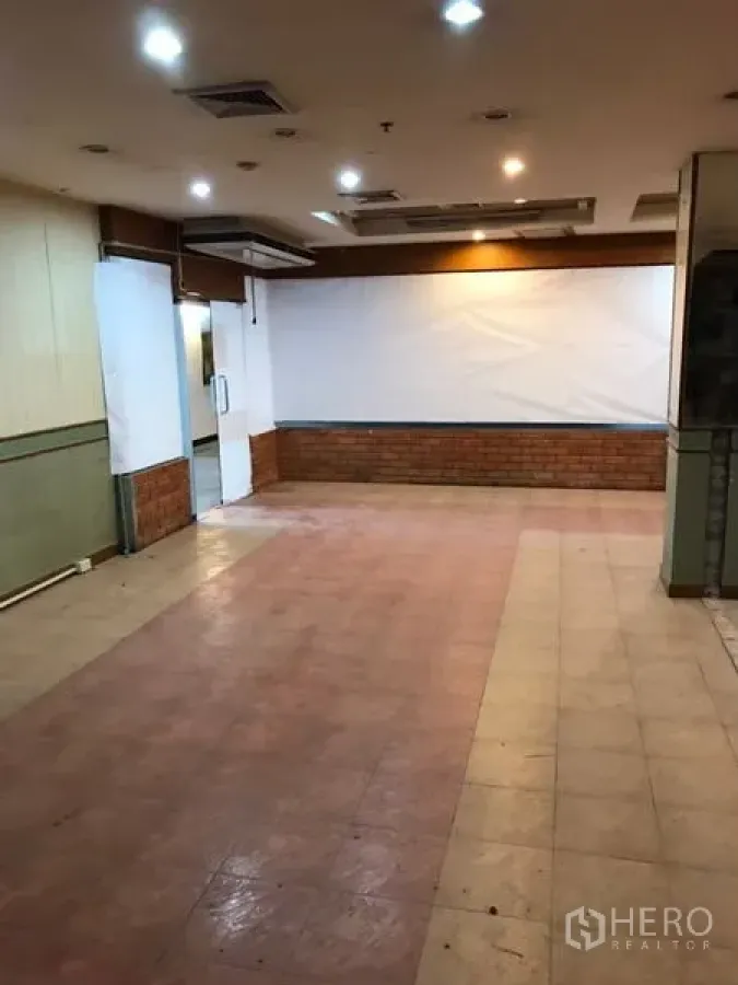 Retail Space for rent in Bang Rak, Bangkok - Open-plan shop interior with spotlight ceiling, rear access door, and brick accent wall near BTS Sala Daeng.