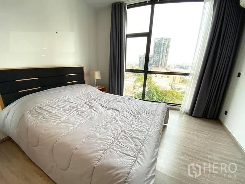 公寓 出租在Watthana, Bangkok - 第二卧室配大窗与窗帘，俯瞰Ekkamai天际线。
