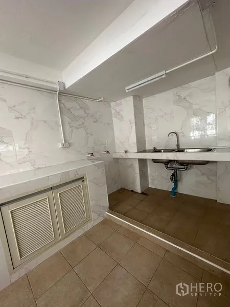 Shophouse for rent in Bangkok - Utility room with marble-look wall tiles, countertop and stainless sink.
