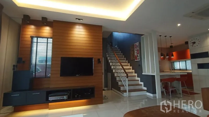 บ้าน ขายในPrawet, Bangkok - พื้นที่นั่งเล่นแบบเปิด ผนังไม้ติดทีวี บันได และครัวพร้อมโคมแขวน