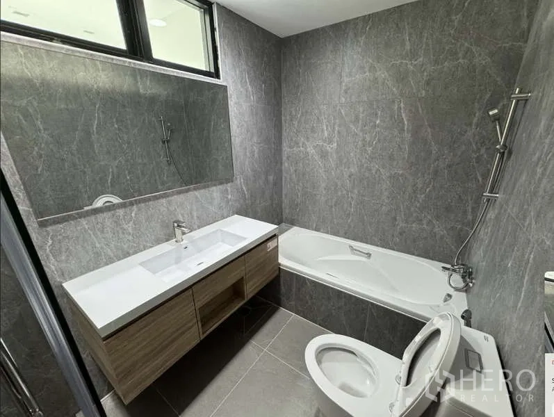 Condominium for rent - Bathroom close-up with double-sink vanity, gray stone walls and bathtub.