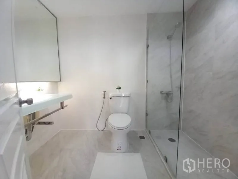 Condominium for rent in Khlong Toei, Bangkok - Clean bathroom with glass-enclosed shower, toilet, and floating vanity.