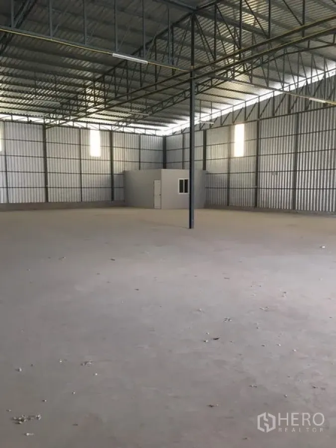 Warehouse for rent in Bang Kapi, Bangkok - Spacious clear-span warehouse interior with high steel truss roof, concrete floor, skylight panels and a small built-in office room.