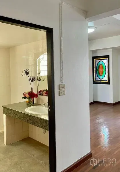 Home Office for rent in Khlong Toei, Bangkok - Bathroom entrance with granite vanity and sink beside corridor with wooden floors.