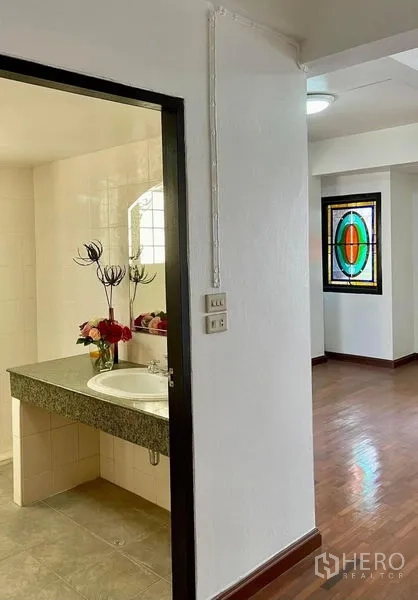 Home Office for rent in Khlong Toei, Bangkok - Bathroom entrance with granite vanity and sink beside corridor with wooden floors.