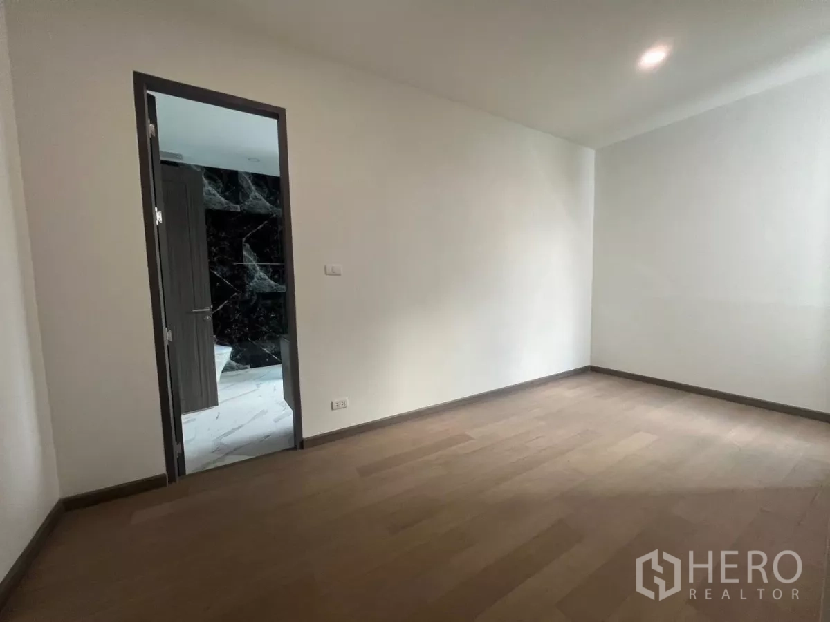 Detached House for rent in Lat Phrao, Bangkok - Secondary bedroom with wood floors and a doorway to an en-suite bathroom with black marble accent.