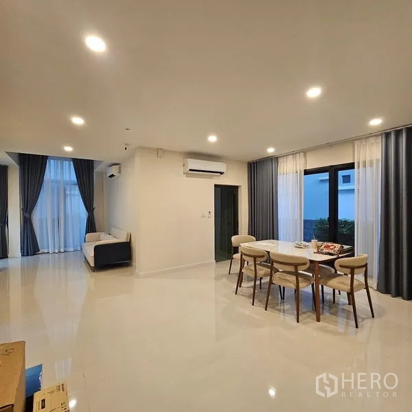 Detached House for rent in Saphan Sung, Bangkok - Open-plan living and dining room with large windows, recessed lighting and glossy tile floors.