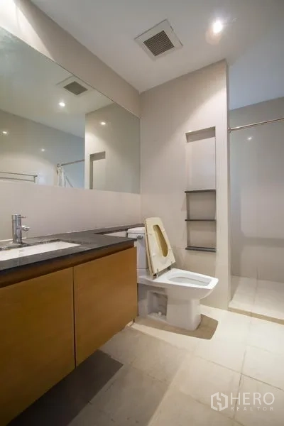 Apartment for rent in Watthana, Bangkok - Guest bathroom with long vanity, large mirror, toilet, and walk-in shower.