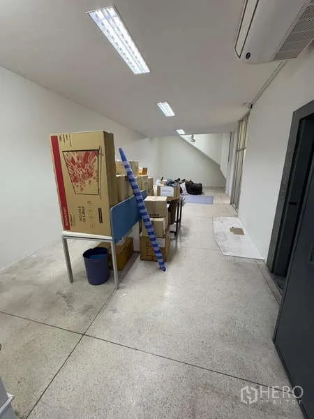 Standalone for rent in Khlong Toei, Bangkok - Long open workspace with fluorescent lighting and storage boxes.