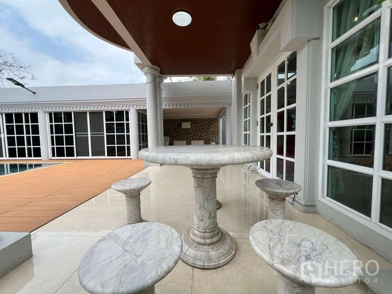 Detached House for rent in Bang Phli, Samut Prakan - Covered patio with round marble table and stools next to French windows by the pool.