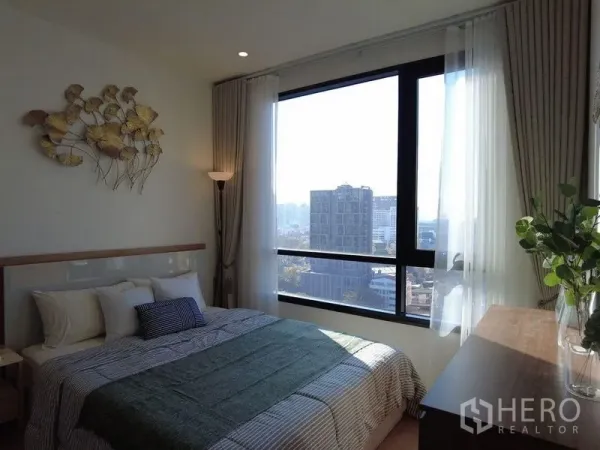 公寓 出售在Watthana, Bangkok - 阳光充足的卧室，墙面装饰、双人床与通高窗户，享受城市景色。