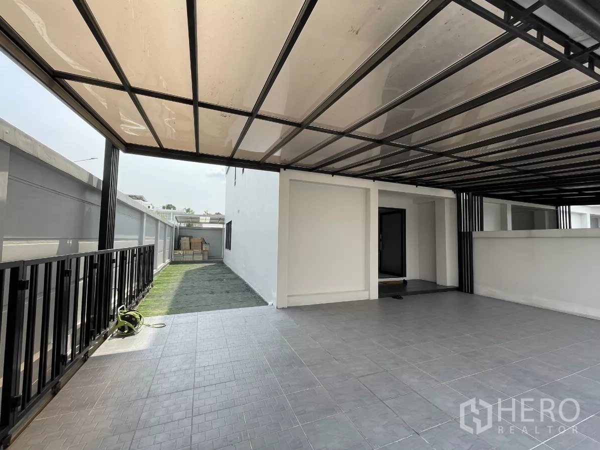 Home Office for rent in Khan Na Yao, Bangkok - Covered carport with tiled floor and a narrow side lawn at the entrance.