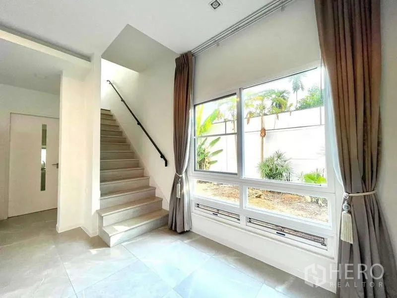 Detached House for rent in Prawet, Bangkok - Staircase with handrail and a big window overlooking the side garden.